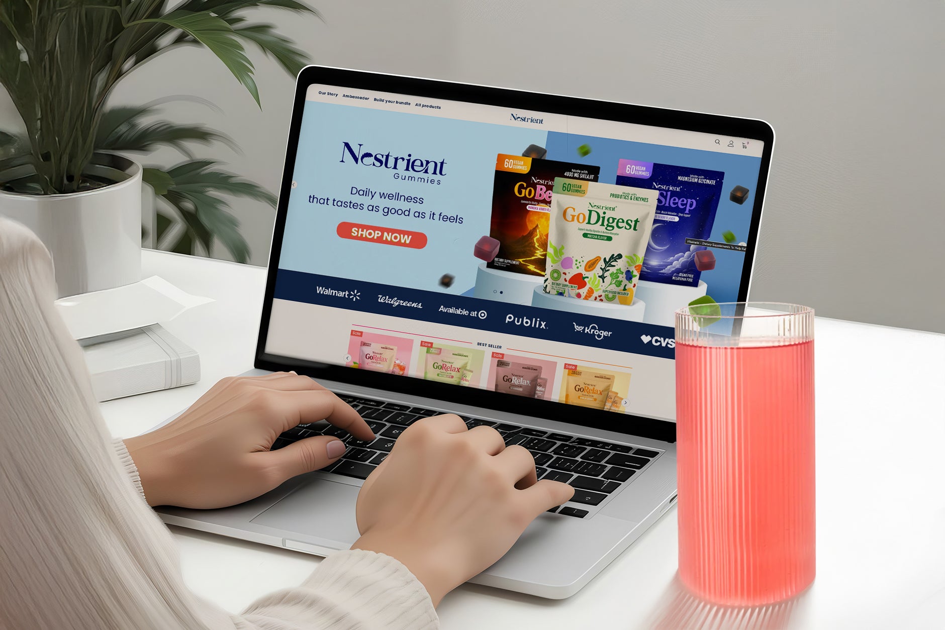 Person using a laptop with Nestlé products displayed on the screen, next to a pink drink.