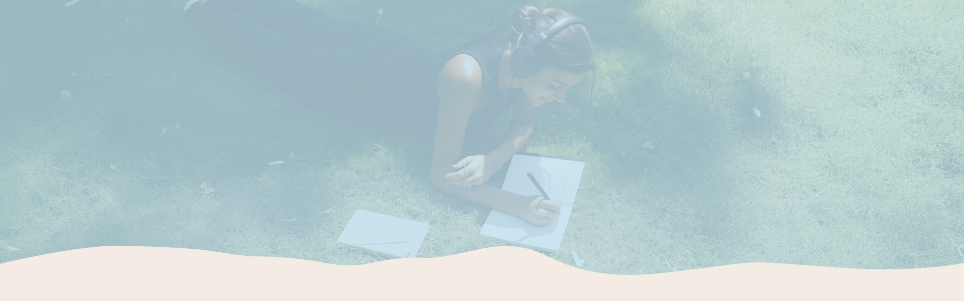 Person sitting on a beach with a laptop, surrounded by greenery